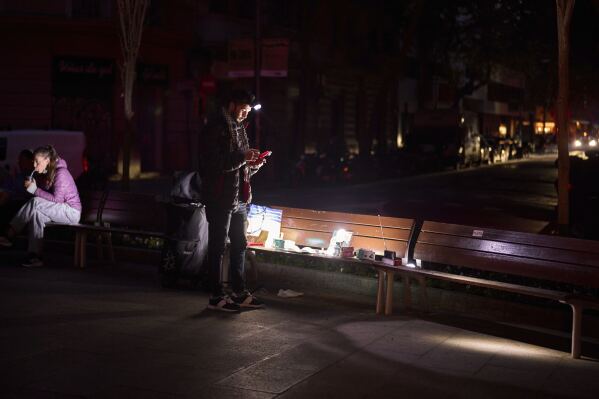 A man sells battery-powered radios and torches on a Barcelona street during the blackout in Barcelona, Spain, Tuesday, April 29, 2025. (AP Photo/Emilio Morenatti)